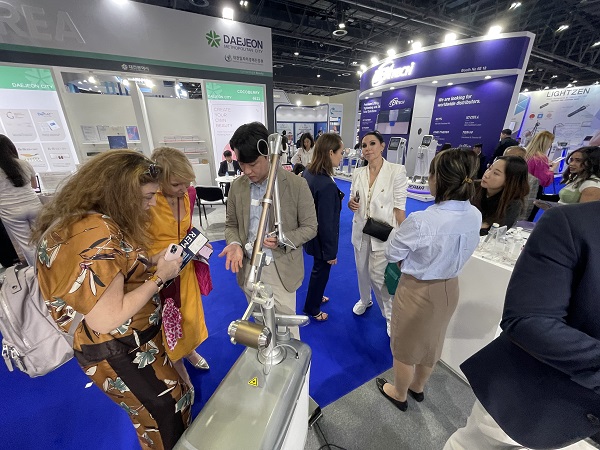 A JSK BioMed representative is explaining Mirajet to Dubai Derma visitors and buyers at their booth.